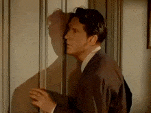 a man in a suit is looking through a door