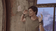 a man stands in front of a window with his hands up