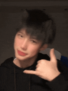 a young man with cat ears on his head is making a hand gesture .