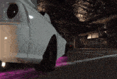 a white car is parked in a garage with a purple light on the bottom of it