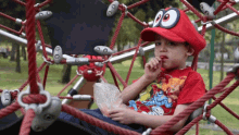 a young boy wearing a red hat and a red shirt with a cartoon character on it