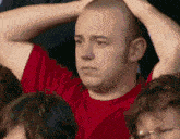 a man in a red shirt is holding his head with his hands