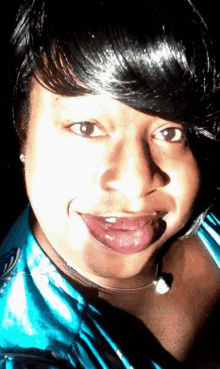 a woman wearing a blue shirt is smiling with her tongue out