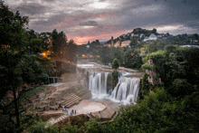 a waterfall is surrounded by a lush green forest