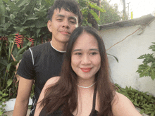 a man and a woman pose for a picture in front of some plants