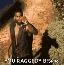 a man with a beard is talking on a cell phone and says " you raggedy b! $ @ & "