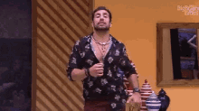 a man with a beard and a floral shirt is standing in a room .