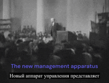 a blurred image of a man giving a speech with the words " the new management apparatus " above him