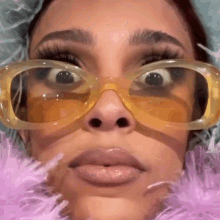 a close up of a woman 's face wearing sunglasses and a pink feather boa .