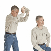 a man in a tan shirt is standing and holding a large rock