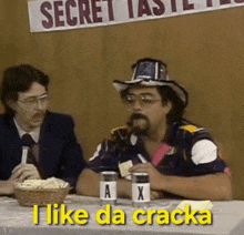 two men are sitting at a table and one of them is saying i like da cracka