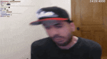a man wearing a hat and a black shirt is looking at the camera .