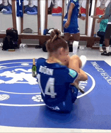 a woman wearing a number 14 jersey sits on the floor