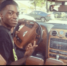 a man is sitting in a bentley car and giving the middle finger