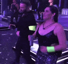 a man and a woman are dancing in a club . the woman is wearing neon green wristbands .