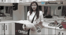 a woman standing in a kitchen with a campus sign on the wall