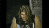 a man with long curly hair is sitting in a dark room .
