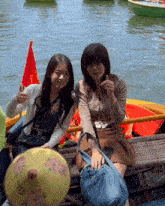 two women sitting on a boat with one holding an umbrella that says ' s ' on it
