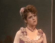 a woman in a purple dress with a flower in her hair is making a funny face .