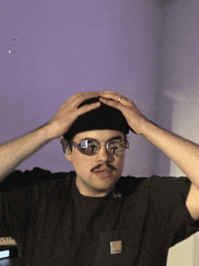 a man wearing sunglasses and a black shirt with a pocket that says carhartt on it