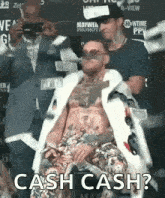 a man in a fur coat and sunglasses is sitting in a chair with the words `` cash cash '' written on the bottom .