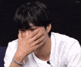 a man in a white shirt is covering his face with his hand ..