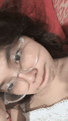 a woman wearing clear glasses is laying down on a bed