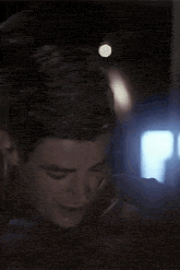 a close up of a man 's face in a dark room with a blurred background .