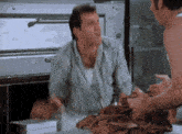 two men are standing next to each other in a kitchen and one of them is holding a piece of paper .