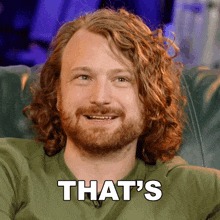 a man with curly hair and a beard is smiling and says that 's in white letters