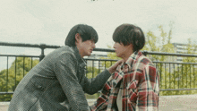 a man in a plaid shirt is touching another man 's chest