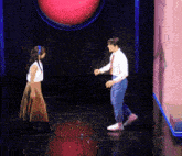 a man and a woman are dancing on a stage in front of a red button