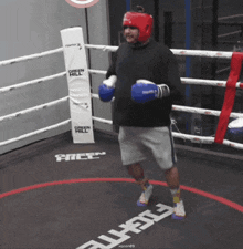 a man wearing boxing gloves is in a boxing ring with a green hill padding