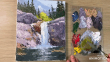 a painting of a waterfall next to a palette of paints
