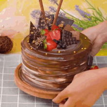 a person is cutting a chocolate cake with strawberries and chocolate shavings