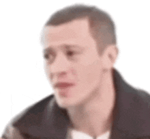 a man with a shaved head is wearing a black jacket and looking at the camera .