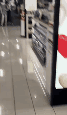a blurred image of people walking in a store with a red heart in the background
