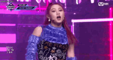 a woman with red hair is standing on a stage wearing a blue top that says `` me first '' .