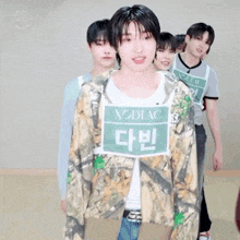 a group of young men are standing next to each other and one of them is wearing a shirt that says zodiac