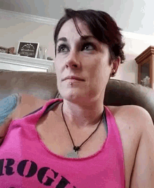 a woman wearing a pink tank top that says ' rogi ' on it
