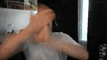 a man in a white shirt is standing in front of a window in a room .