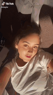 a woman in a white shirt is taking a selfie with a tik tok watermark