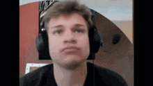 a young man wearing headphones and a microphone looks at the camera .