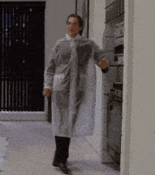 a man in a white coat is standing in a hallway .
