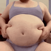 a woman in a purple bra and purple underwear is holding her stomach .