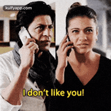 a man and a woman are talking on cell phones and the woman is saying `` i don 't like you '' .