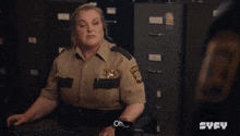 a woman in a sheriff 's uniform sits at a desk with a keyboard and says oh