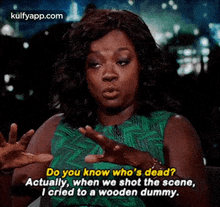 a woman in a green dress is talking to a wooden dummy while holding her hands up .