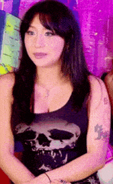 a woman wearing a black tank top with a skull and cross on it