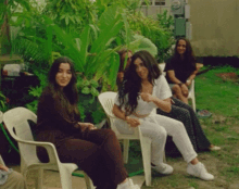 a group of women are sitting in chairs outside